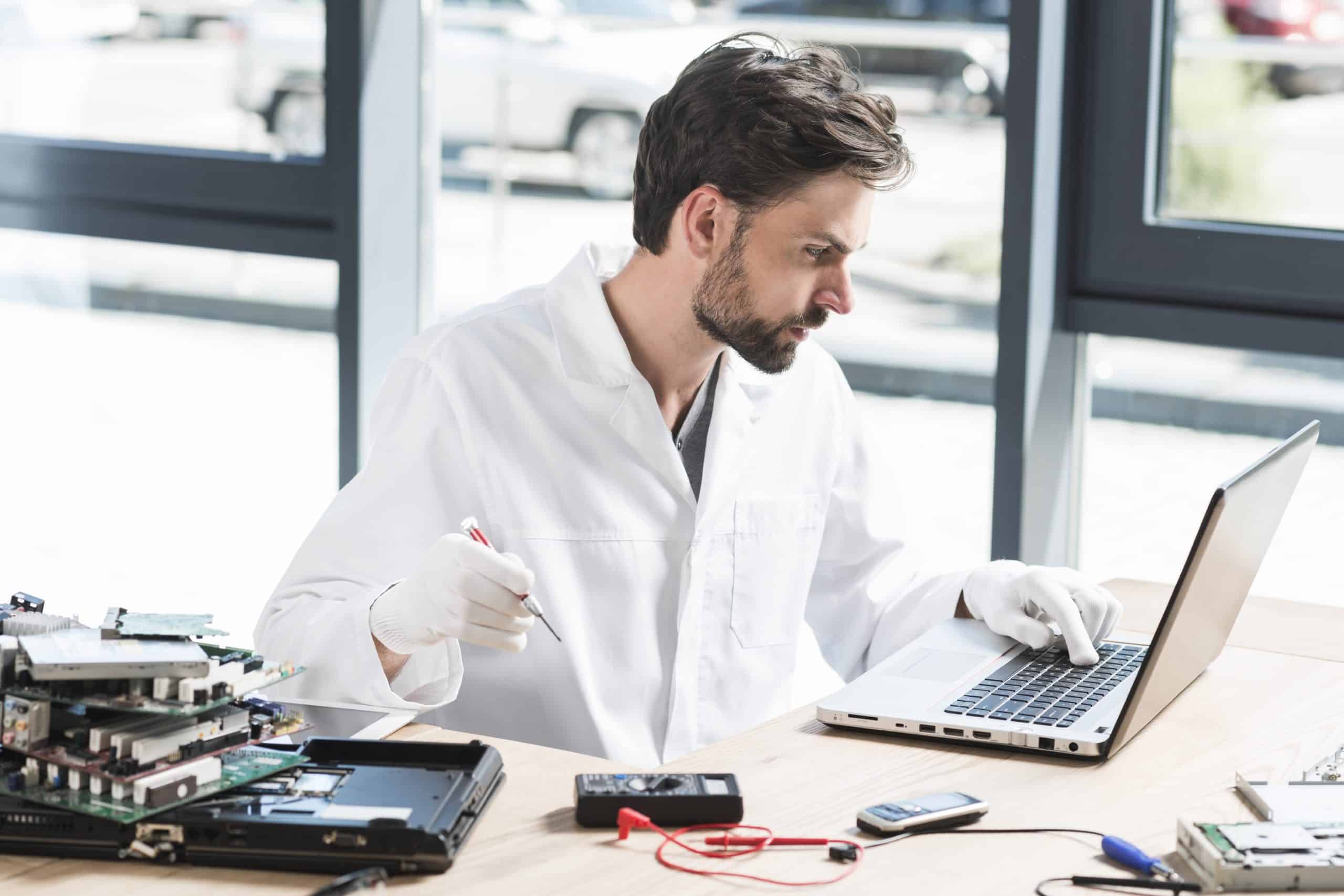 Young male technician using laptop workshop scaled